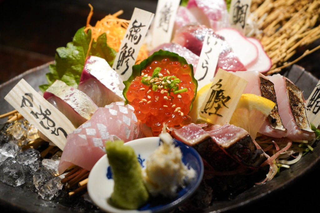 Wooden name tags marking each fish on a sashimi platter